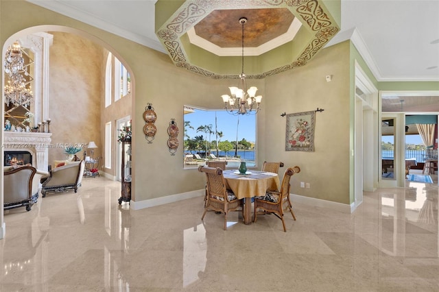 dining room featuring a chandelier, ornamental molding, a glass covered fireplace, and baseboards