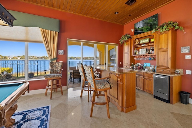 bar featuring a water view, visible vents, wood ceiling, baseboards, and indoor wet bar