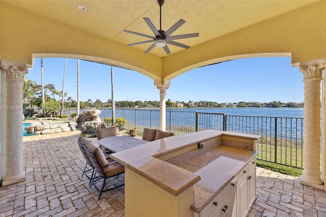 view of patio with a ceiling fan, a water view, fence, and area for grilling