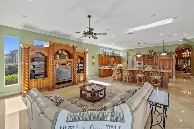 living area with arched walkways, a ceiling fan, baseboards, visible vents, and crown molding