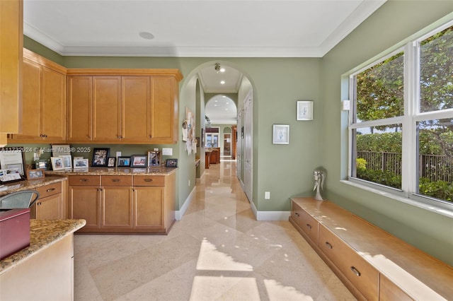 kitchen with arched walkways, recessed lighting, baseboards, brown cabinets, and crown molding