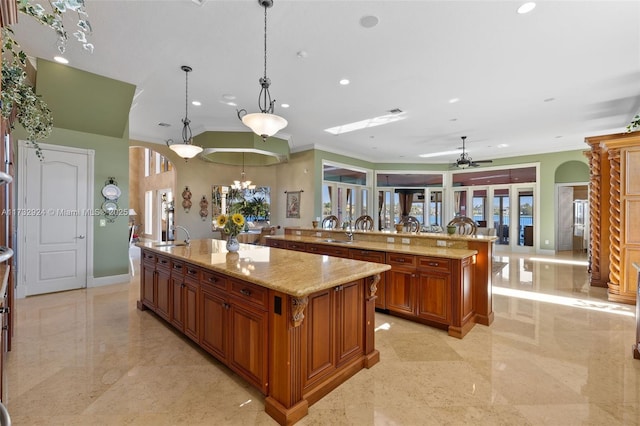 kitchen with arched walkways, hanging light fixtures, a large island, and brown cabinetry