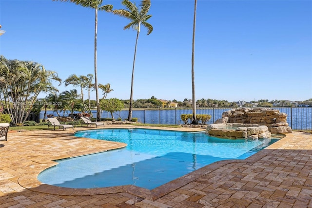 view of pool featuring a pool with connected hot tub, a patio area, a water view, and fence