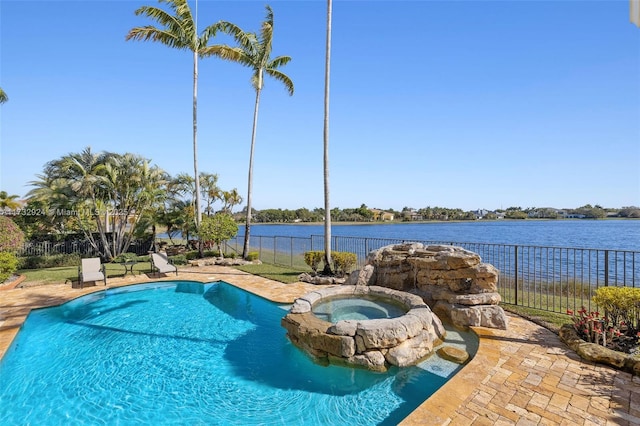 view of pool with a pool with connected hot tub, a water view, and fence