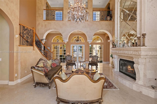 living area with baseboards, a premium fireplace, ornamental molding, and a notable chandelier