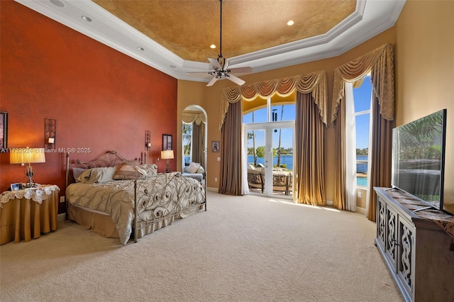 bedroom with access to exterior, a tray ceiling, ornamental molding, and carpet floors