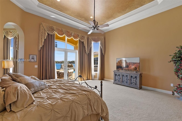 carpeted bedroom featuring baseboards, arched walkways, a raised ceiling, access to exterior, and crown molding