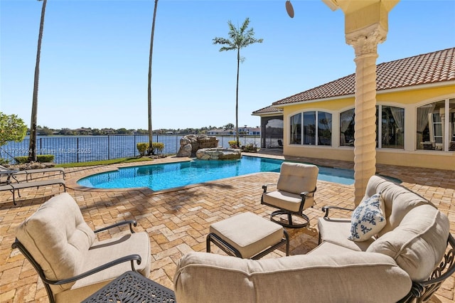 view of swimming pool featuring a pool with connected hot tub, a water view, fence, and a patio