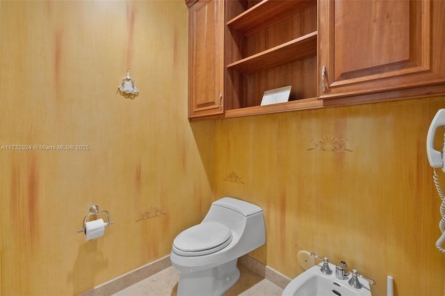 bathroom with a bidet, toilet, and baseboards