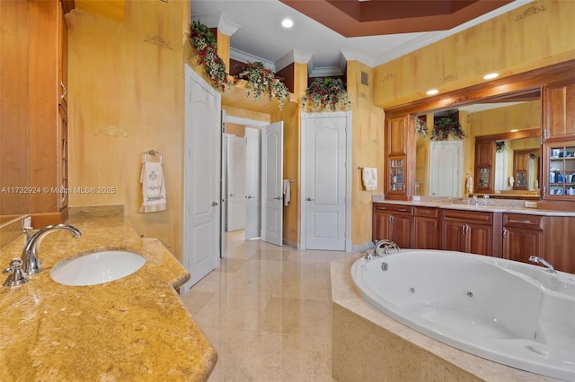 bathroom featuring crown molding, a tub with jets, two vanities, and a sink