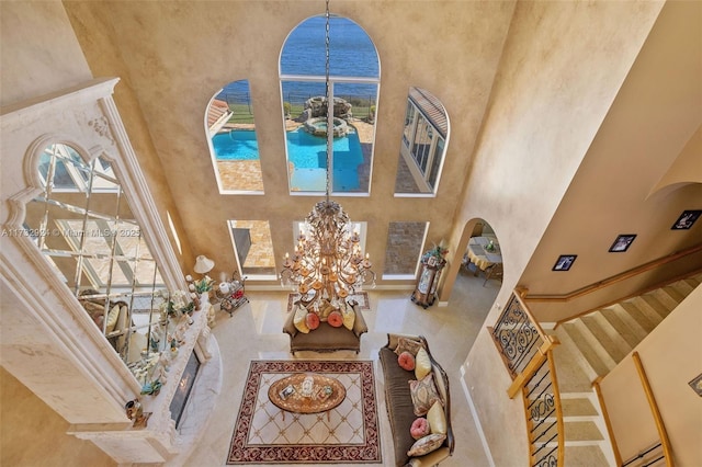 living room featuring a high ceiling, a water view, and an inviting chandelier