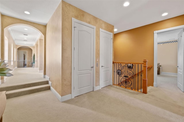 corridor with arched walkways, recessed lighting, baseboards, and light colored carpet