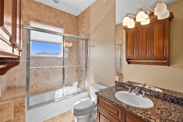 bathroom featuring combined bath / shower with glass door, a notable chandelier, vanity, and toilet