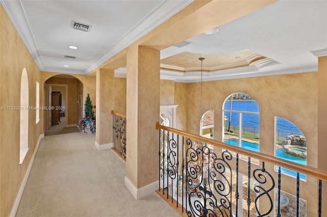 corridor featuring visible vents, arched walkways, light colored carpet, a water view, and crown molding