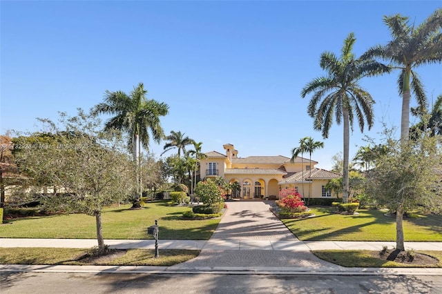 mediterranean / spanish house featuring decorative driveway, a front lawn, and stucco siding