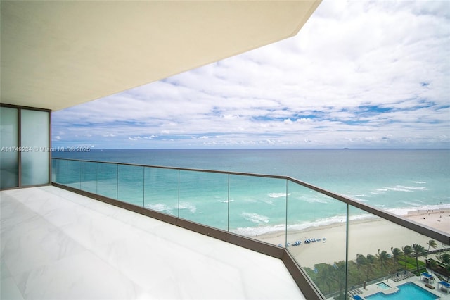 balcony with a water view and a view of the beach