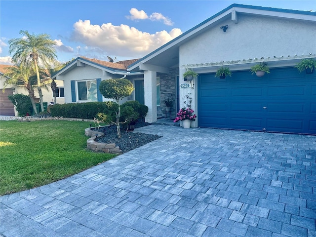 single story home featuring a garage, a front yard, decorative driveway, and stucco siding