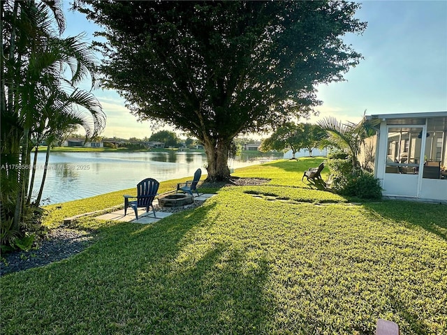 view of yard with an outdoor fire pit, a sunroom, and a water view