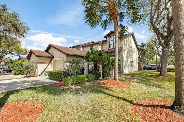 view of front of home with an attached garage, driveway, a front lawn, and stucco siding