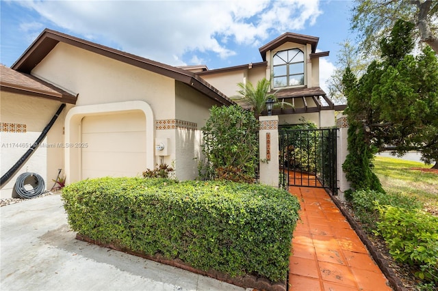 view of front of home with a garage, a gate, and stucco siding