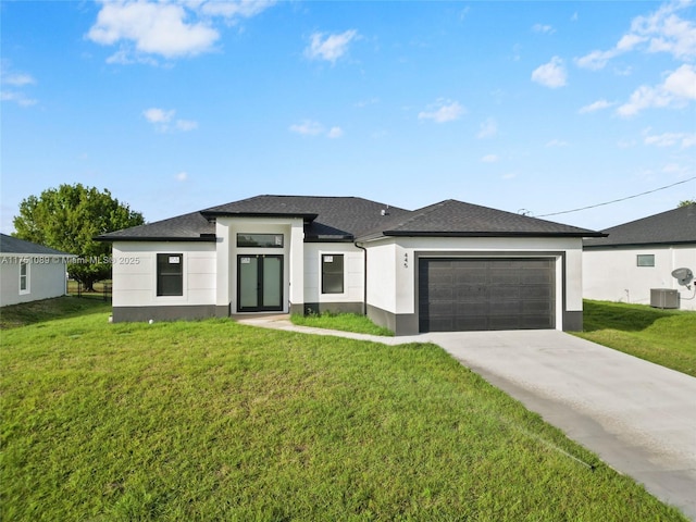 prairie-style home with a front lawn, central AC, an attached garage, and stucco siding