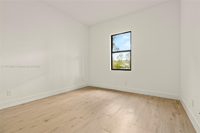 spare room with baseboards and light wood finished floors