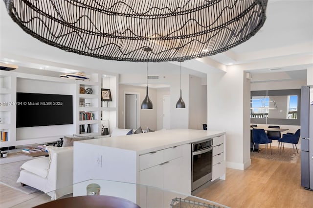 kitchen featuring stainless steel appliances, white cabinetry, open floor plan, light countertops, and pendant lighting