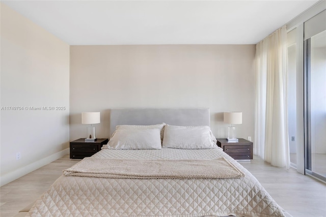 bedroom featuring access to exterior, light wood-style flooring, and baseboards