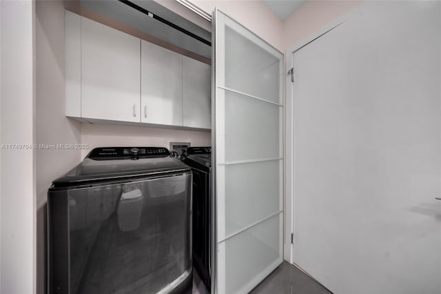 clothes washing area featuring cabinet space and washing machine and clothes dryer