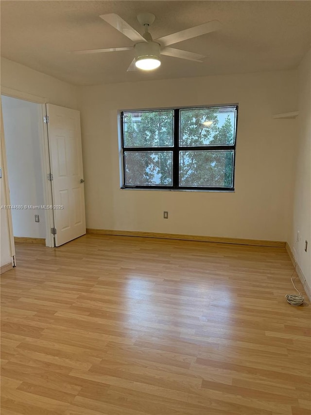 empty room with a ceiling fan, light wood-style flooring, and baseboards