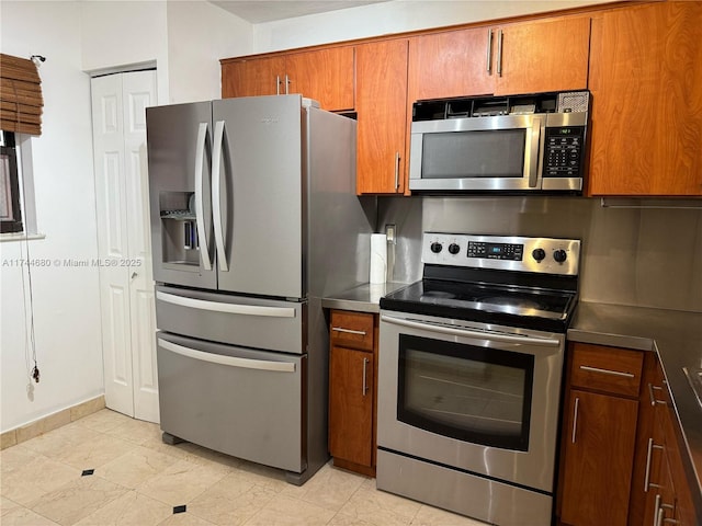 kitchen with stainless steel appliances, dark countertops, brown cabinetry, and decorative backsplash