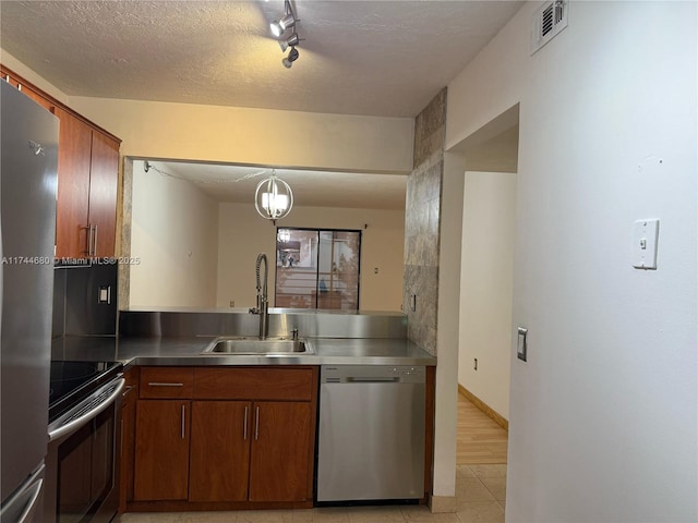 kitchen featuring decorative light fixtures, visible vents, appliances with stainless steel finishes, brown cabinetry, and a sink