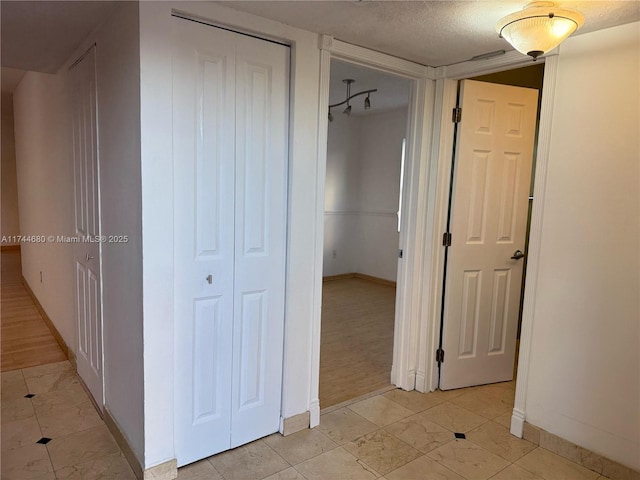 hallway with a textured ceiling and baseboards