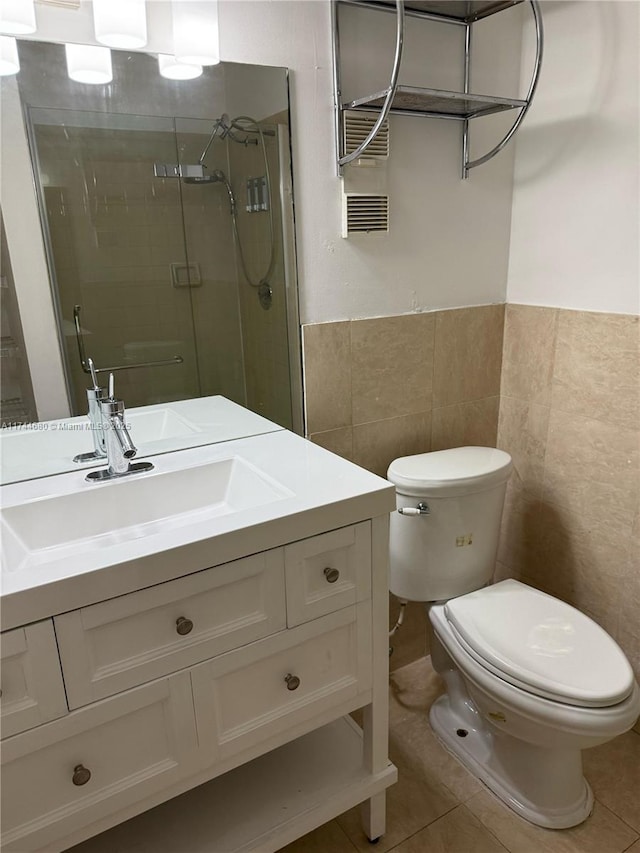 bathroom featuring tile patterned flooring, toilet, vanity, tile walls, and a shower stall