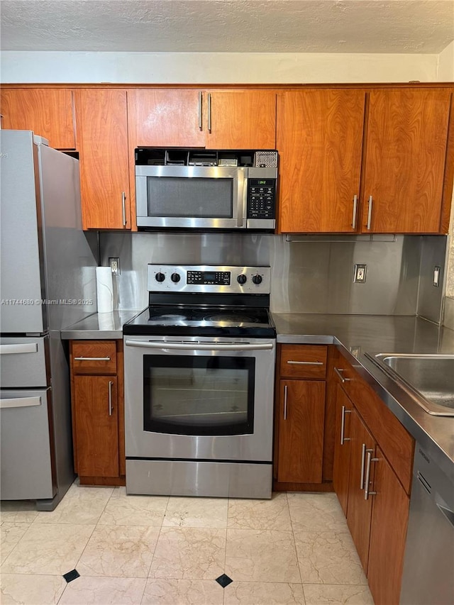 kitchen with marble finish floor, stainless steel counters, appliances with stainless steel finishes, and brown cabinetry