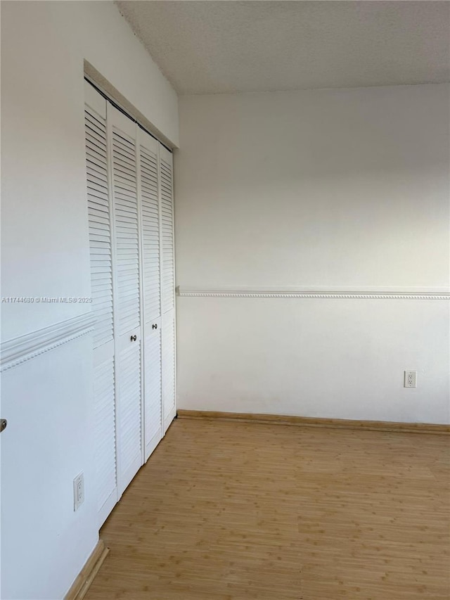 unfurnished bedroom with a closet, wood finished floors, and baseboards