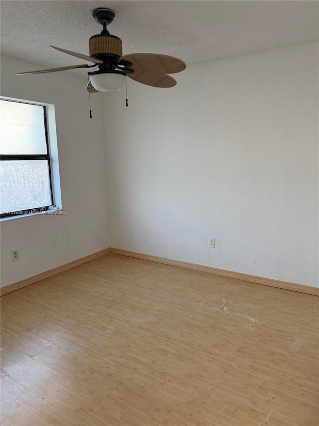 empty room featuring light wood finished floors, a ceiling fan, baseboards, and a textured ceiling