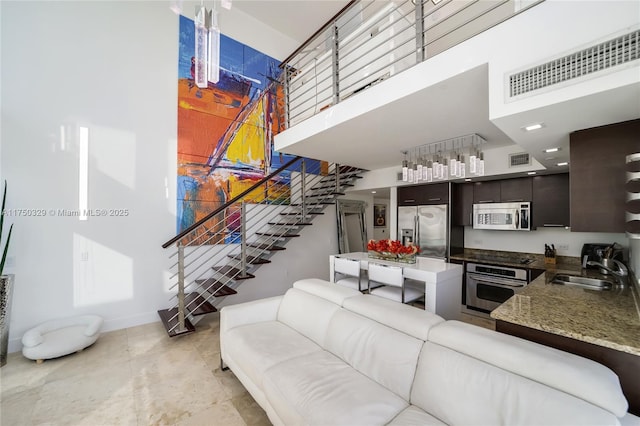 living room featuring a towering ceiling, stairs, and visible vents