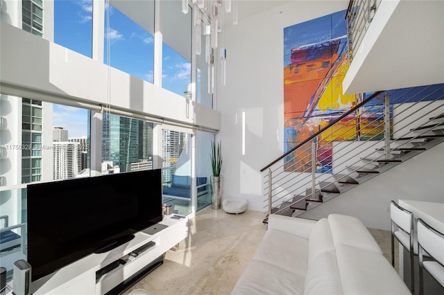 living area with concrete flooring, a high ceiling, and stairway