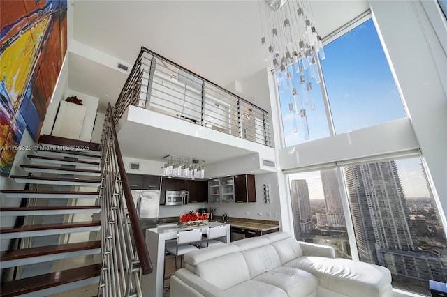 living area featuring stairs, a high ceiling, and visible vents