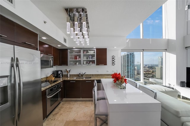 kitchen with a city view, appliances with stainless steel finishes, glass insert cabinets, a sink, and modern cabinets