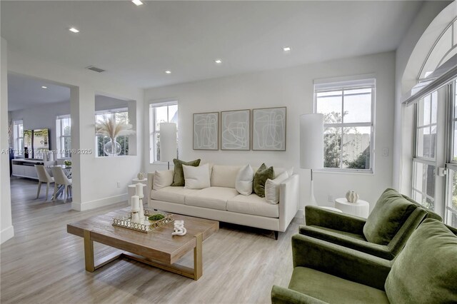 living room with light wood finished floors, visible vents, baseboards, and recessed lighting