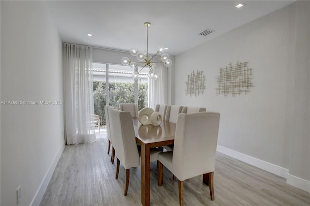 dining area with visible vents, baseboards, a chandelier, and wood finished floors