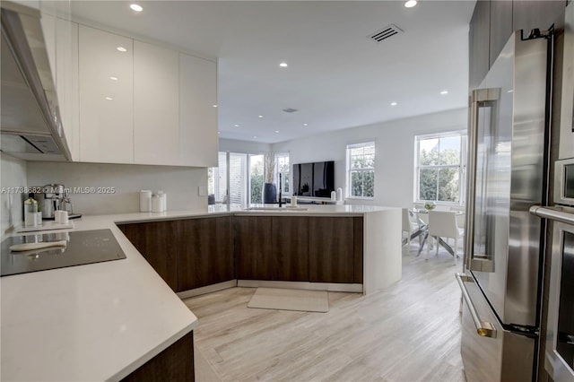 kitchen featuring black electric stovetop, visible vents, white cabinets, light countertops, and modern cabinets