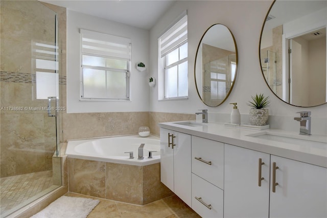 bathroom with a stall shower, a garden tub, a sink, and double vanity