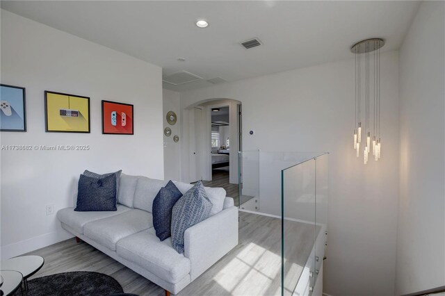 living area featuring visible vents, arched walkways, baseboards, light wood-style flooring, and recessed lighting