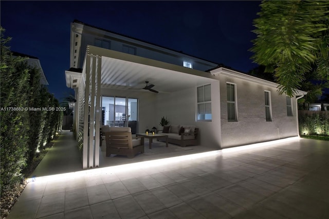 patio at twilight with ceiling fan and an outdoor living space