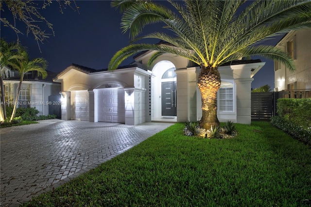 view of front of house with decorative driveway, a yard, and fence