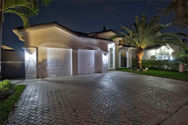 mediterranean / spanish house featuring a garage, decorative driveway, and stucco siding