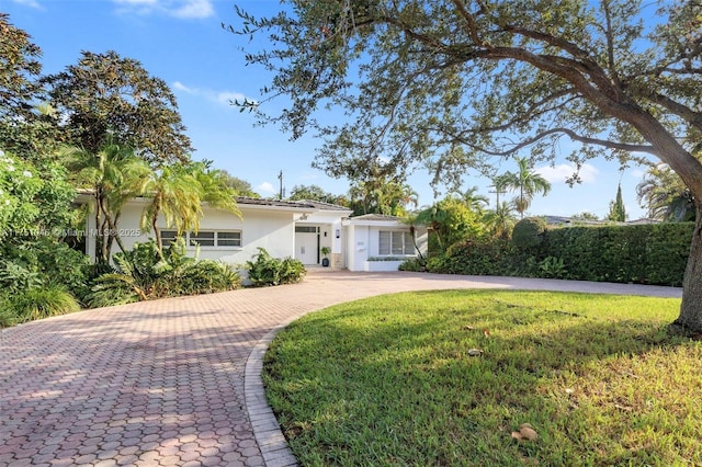 ranch-style home with stucco siding, decorative driveway, and a front yard